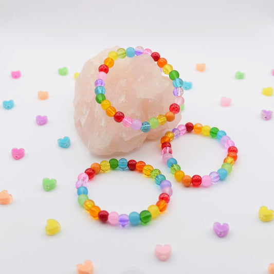 Colorful beaded bracelets on a white background with small heart-shaped beads scattered around.