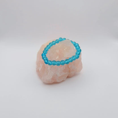 Blue/Turquoise beaded bracelet on a pink stone with a white background