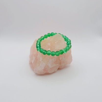 Green/Aqua beaded bracelet on a pink stone with a white background