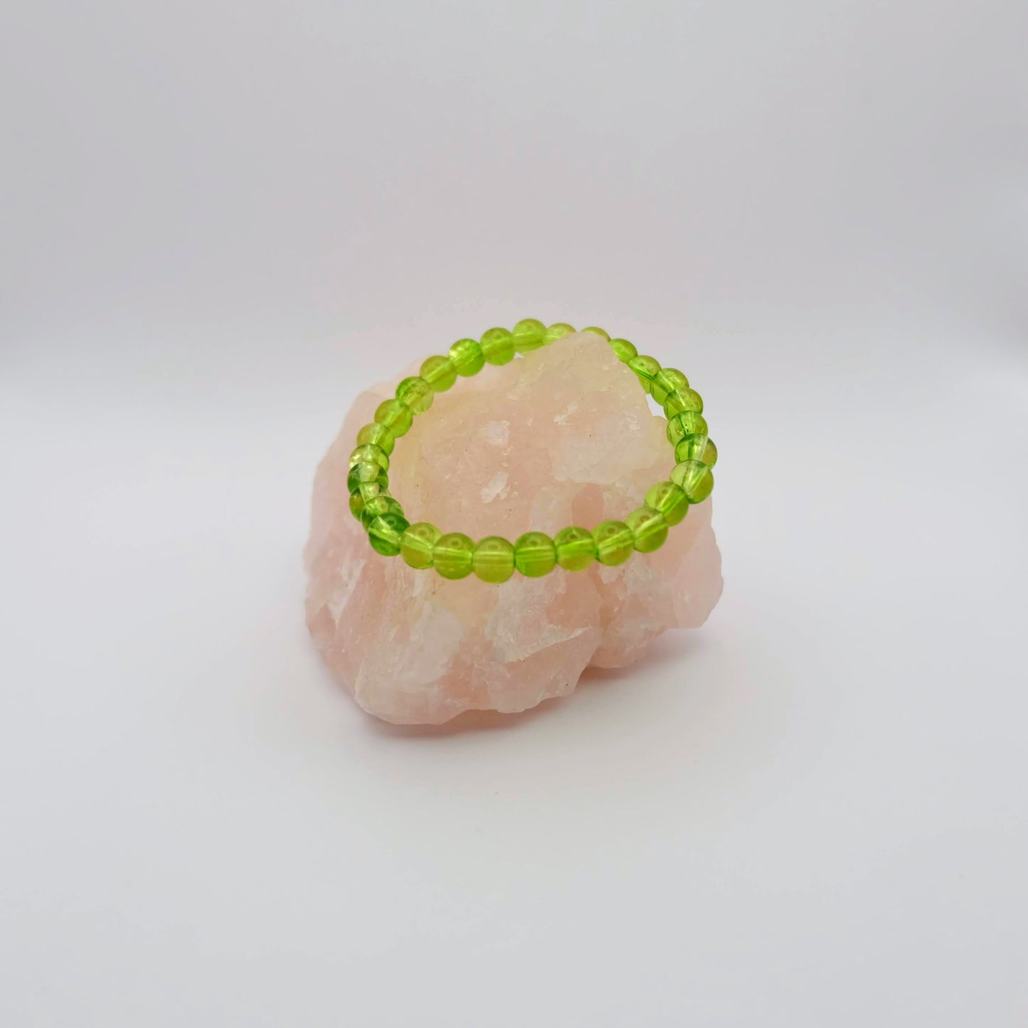 Green beaded bracelet on a pink stone with a white background