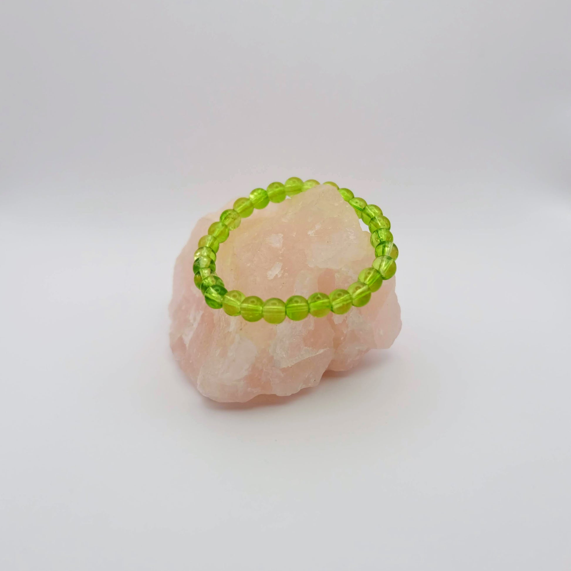 Green beaded bracelet on a pink stone with a white background