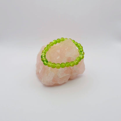 Green beaded bracelet on a pink stone with a white background
