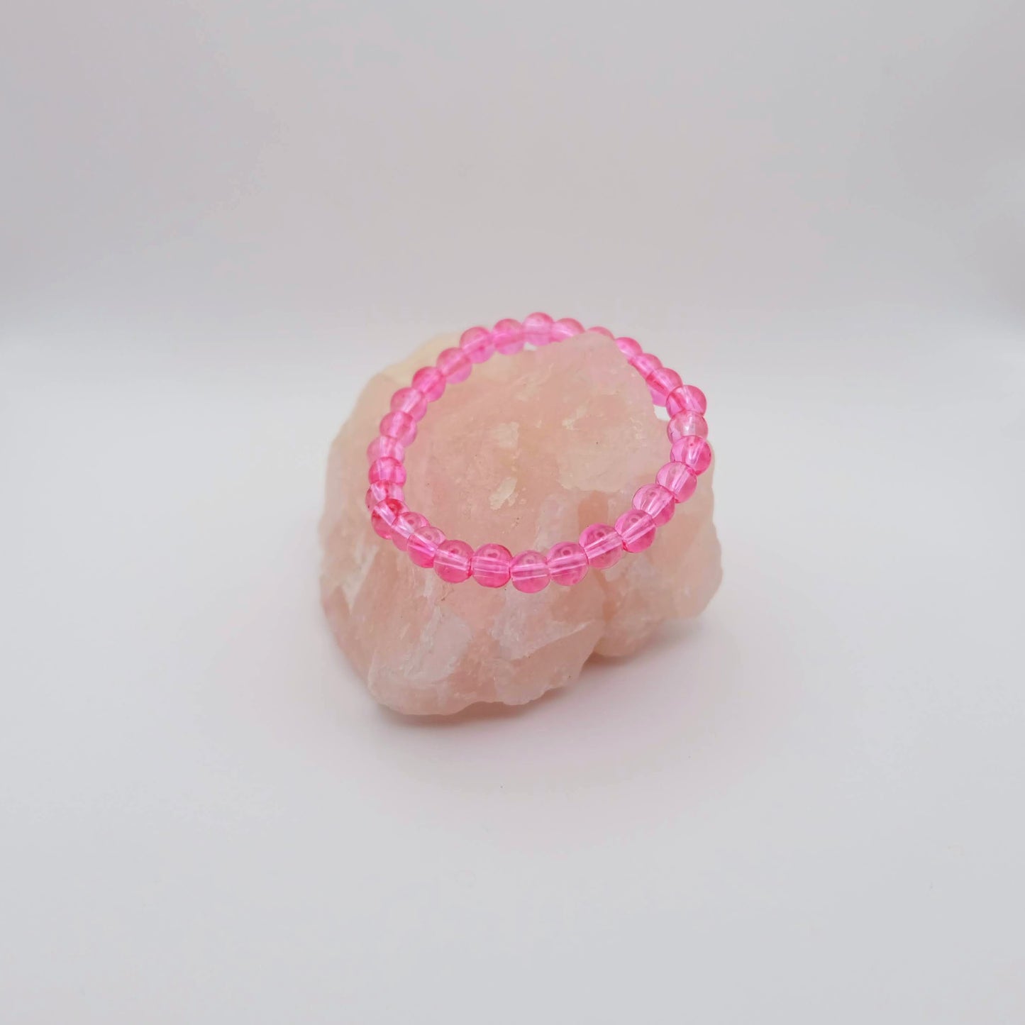 Pink beaded ring on a textured beige surface with a white background