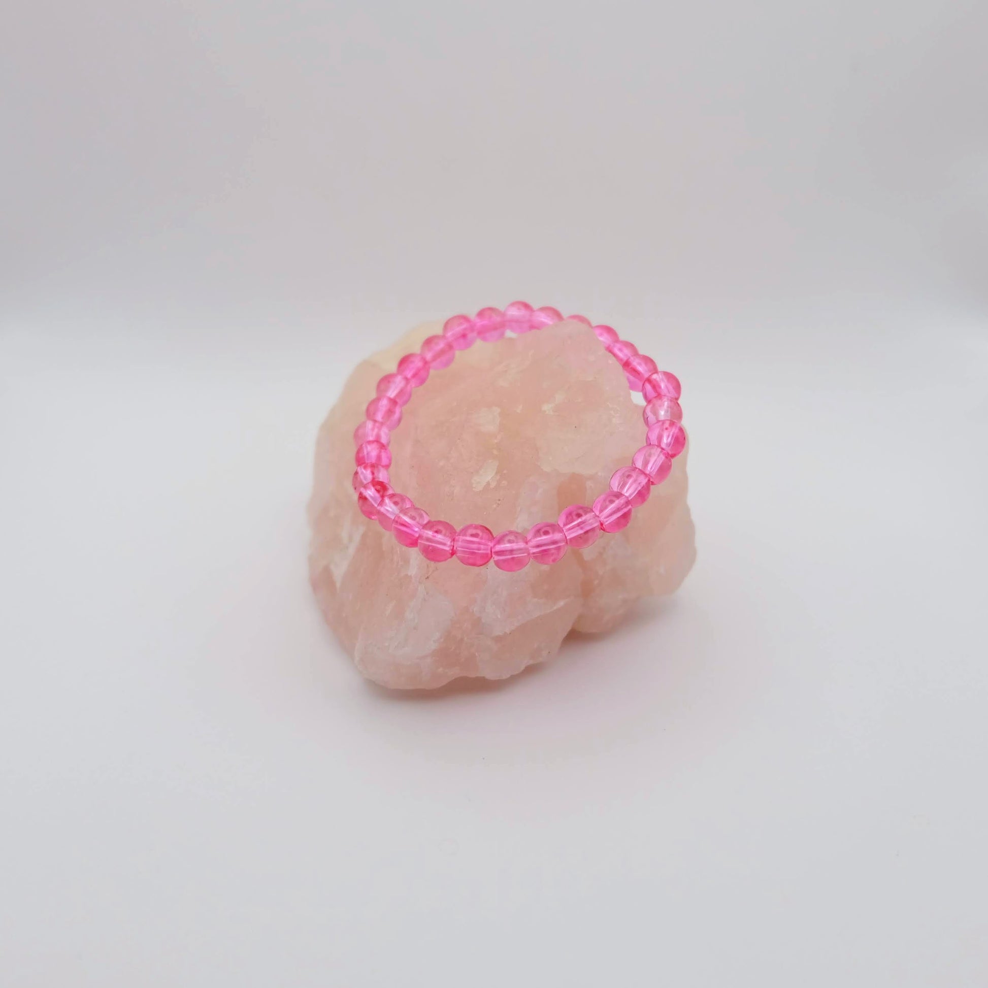 Pink beaded ring on a textured beige surface with a white background