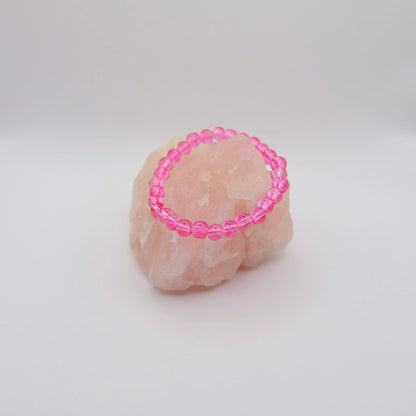 Pink beaded ring on a textured beige surface with a white background