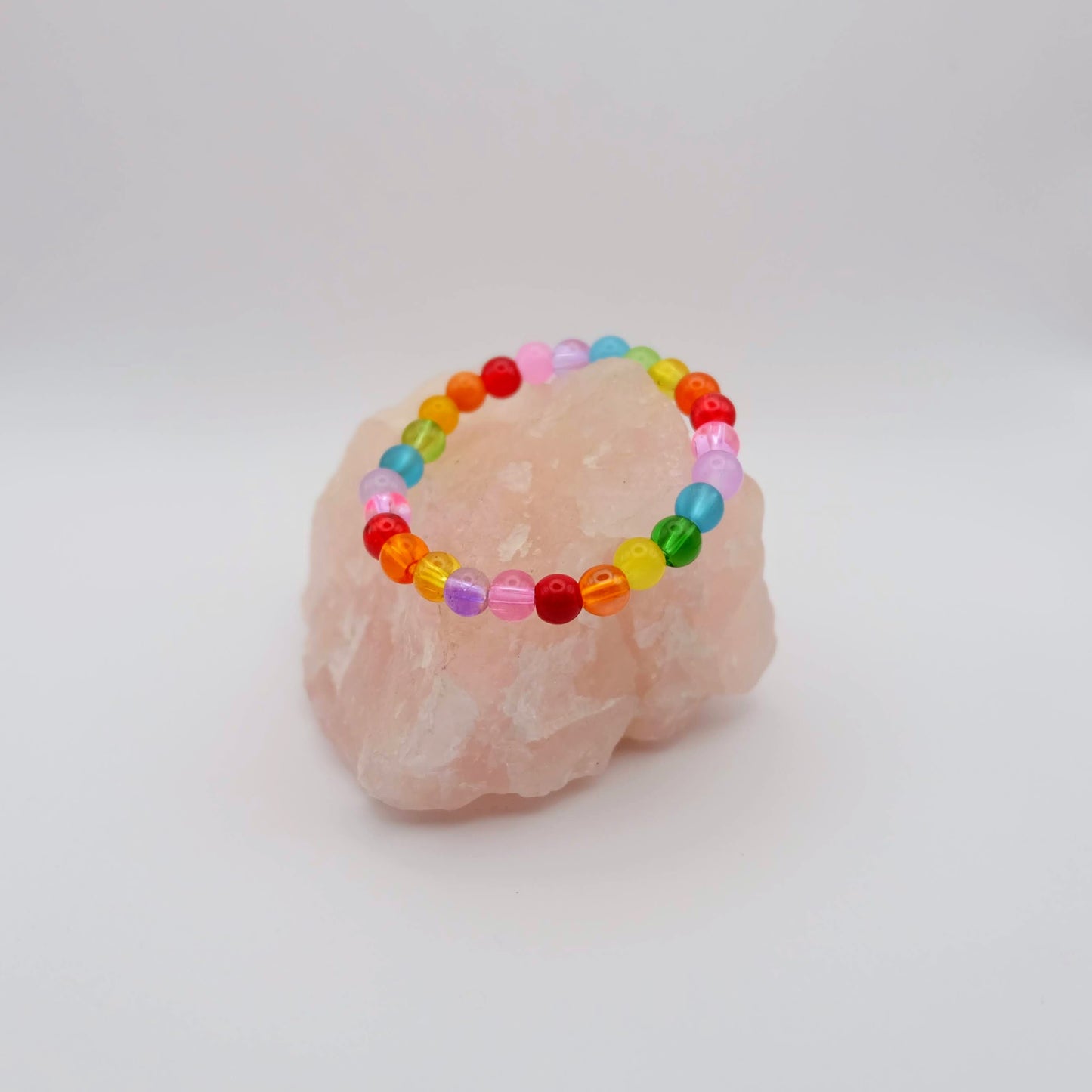 Colorful beaded bracelet on a pink stone with a white background