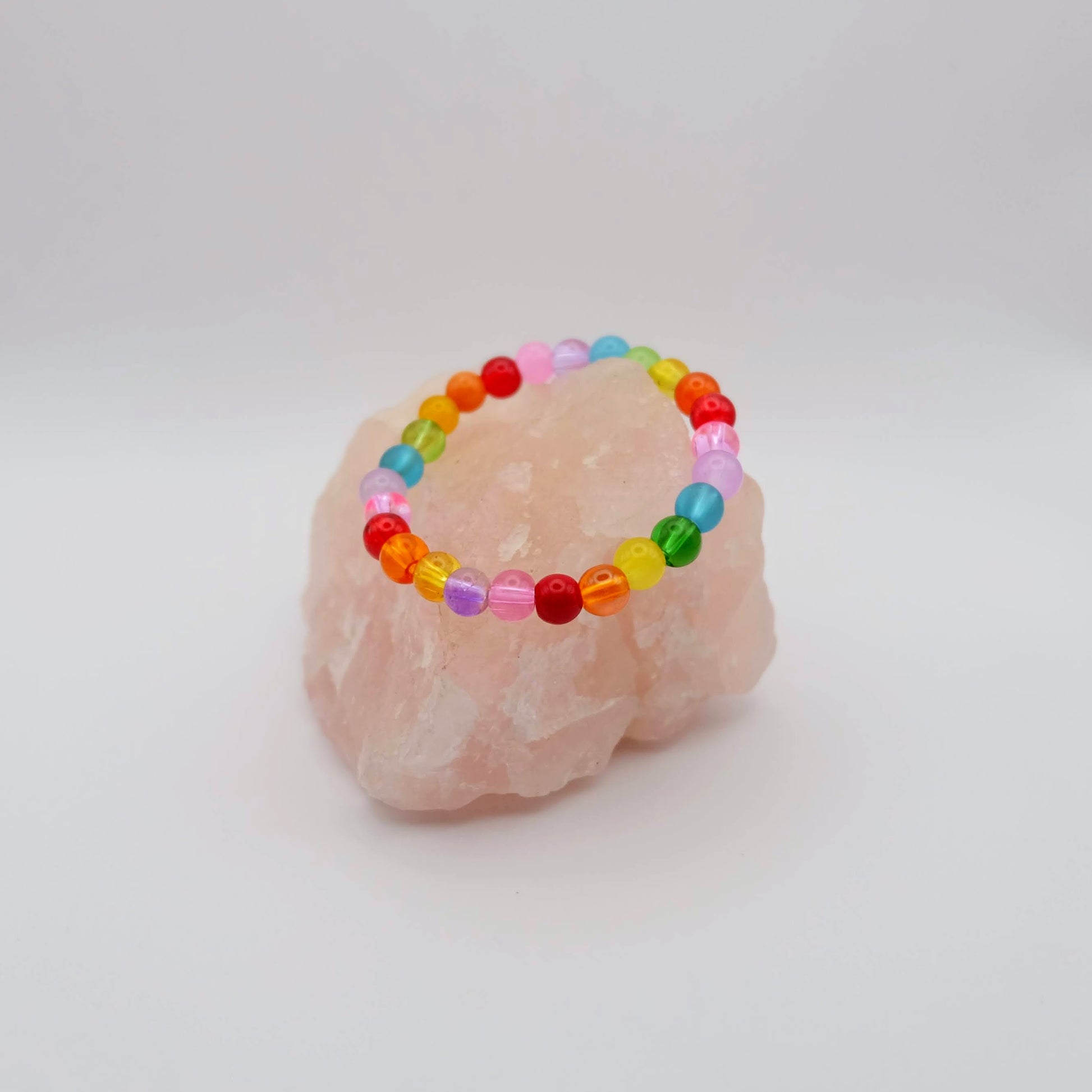 Colorful beaded bracelet on a pink stone with a white background