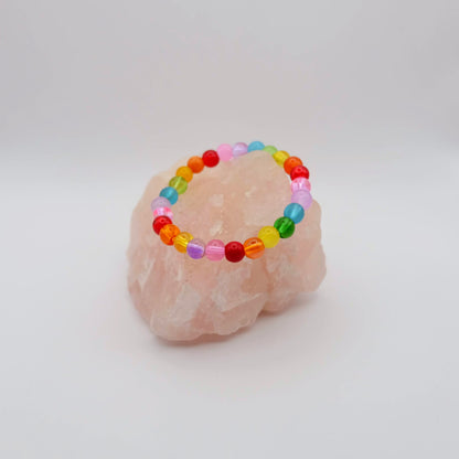 Colorful beaded bracelet on a pink stone with a white background