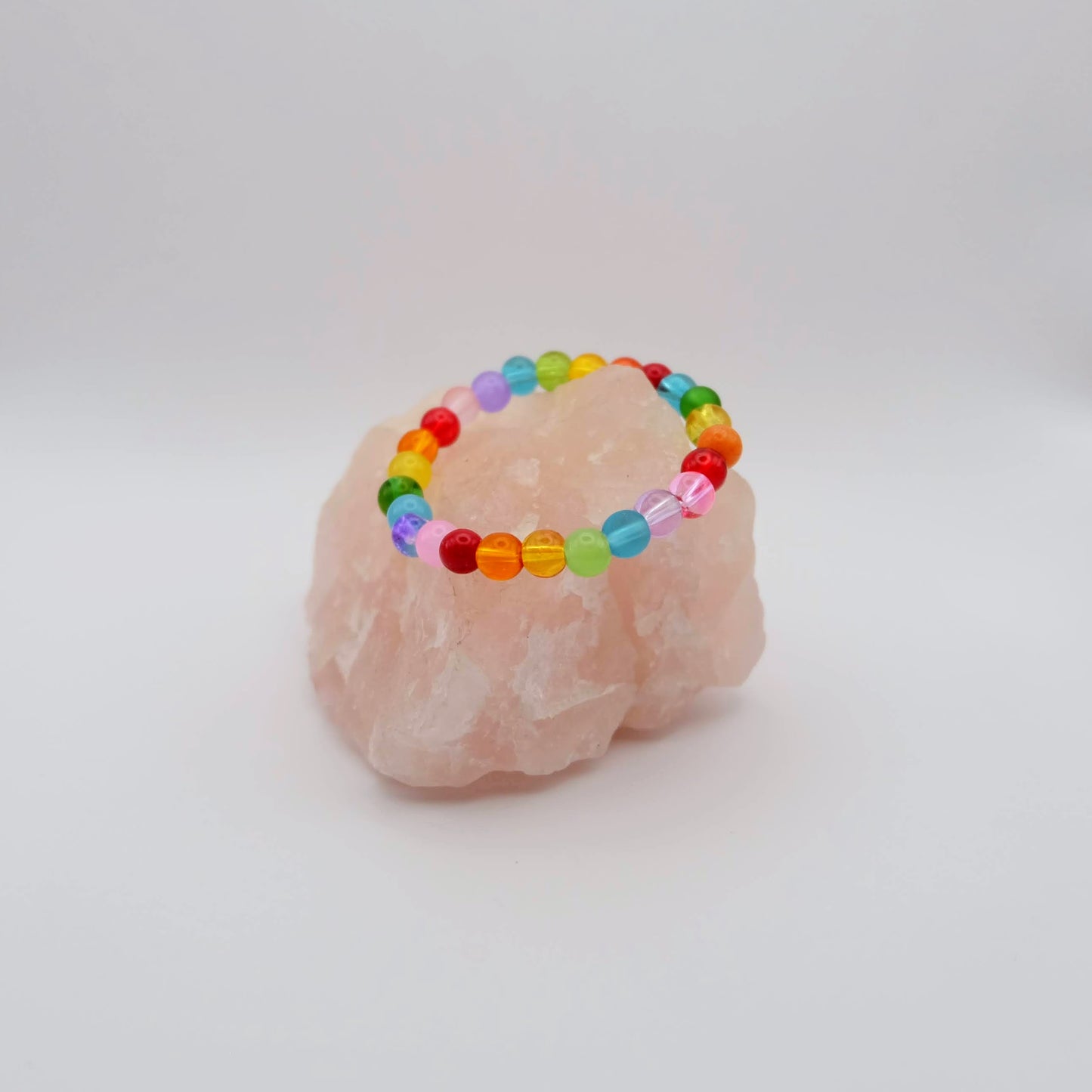 Colorful beaded bracelet on a pink crystal with a white background