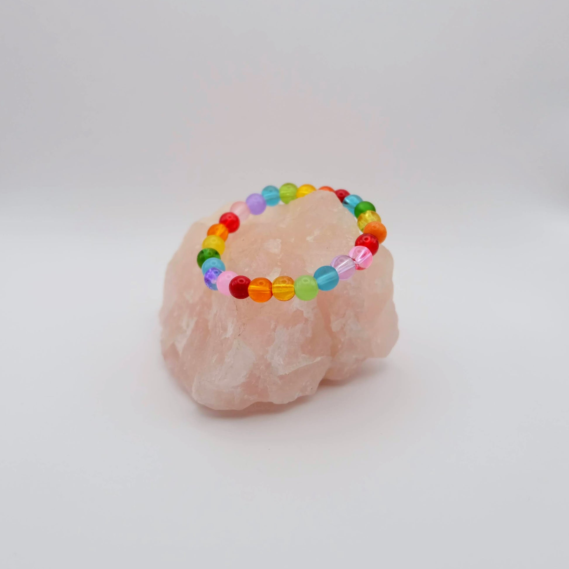 Colorful beaded bracelet on a pink crystal with a white background