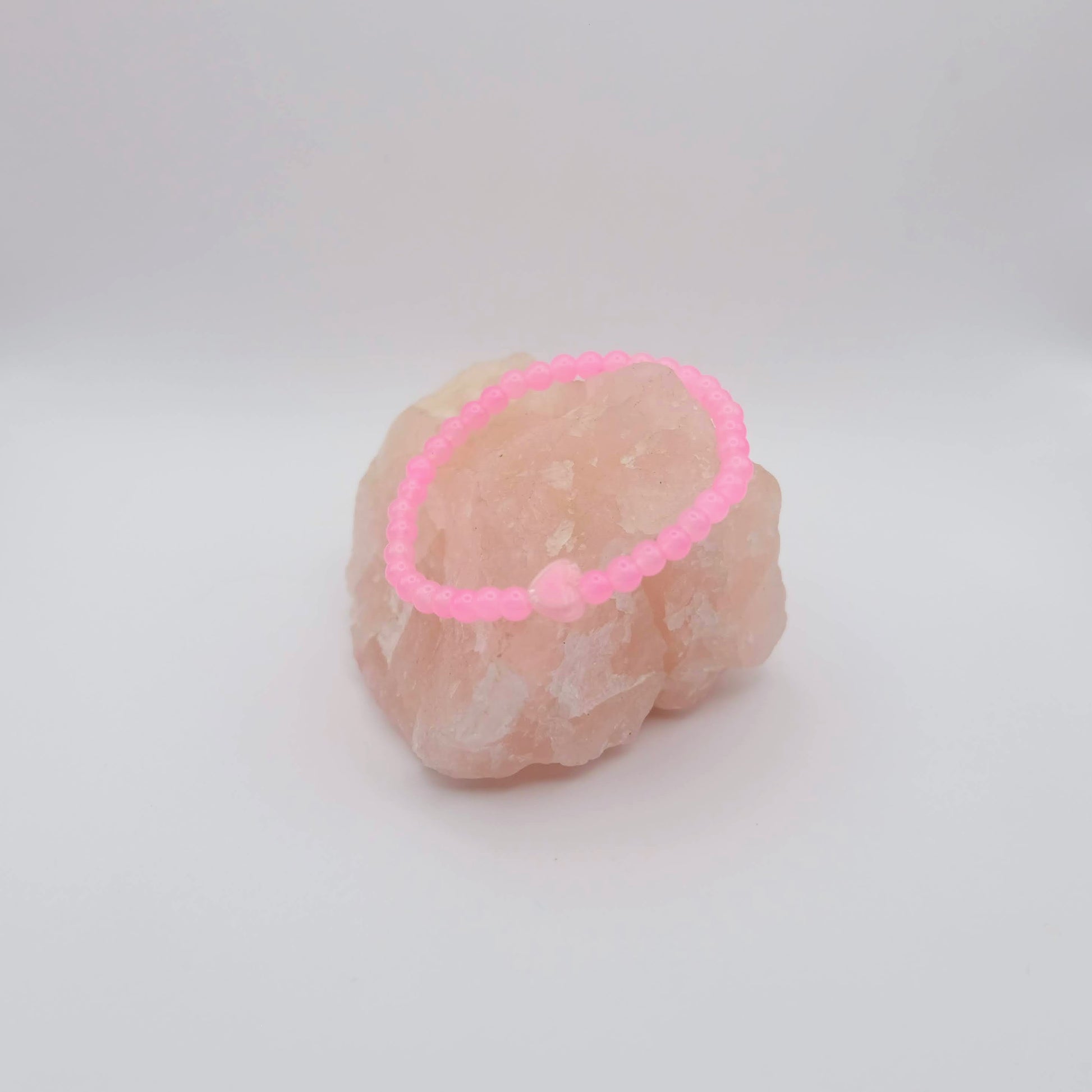 Pink beaded bracelet on a pink stone against a white background