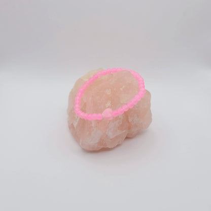 Pink beaded bracelet on a pink stone against a white background