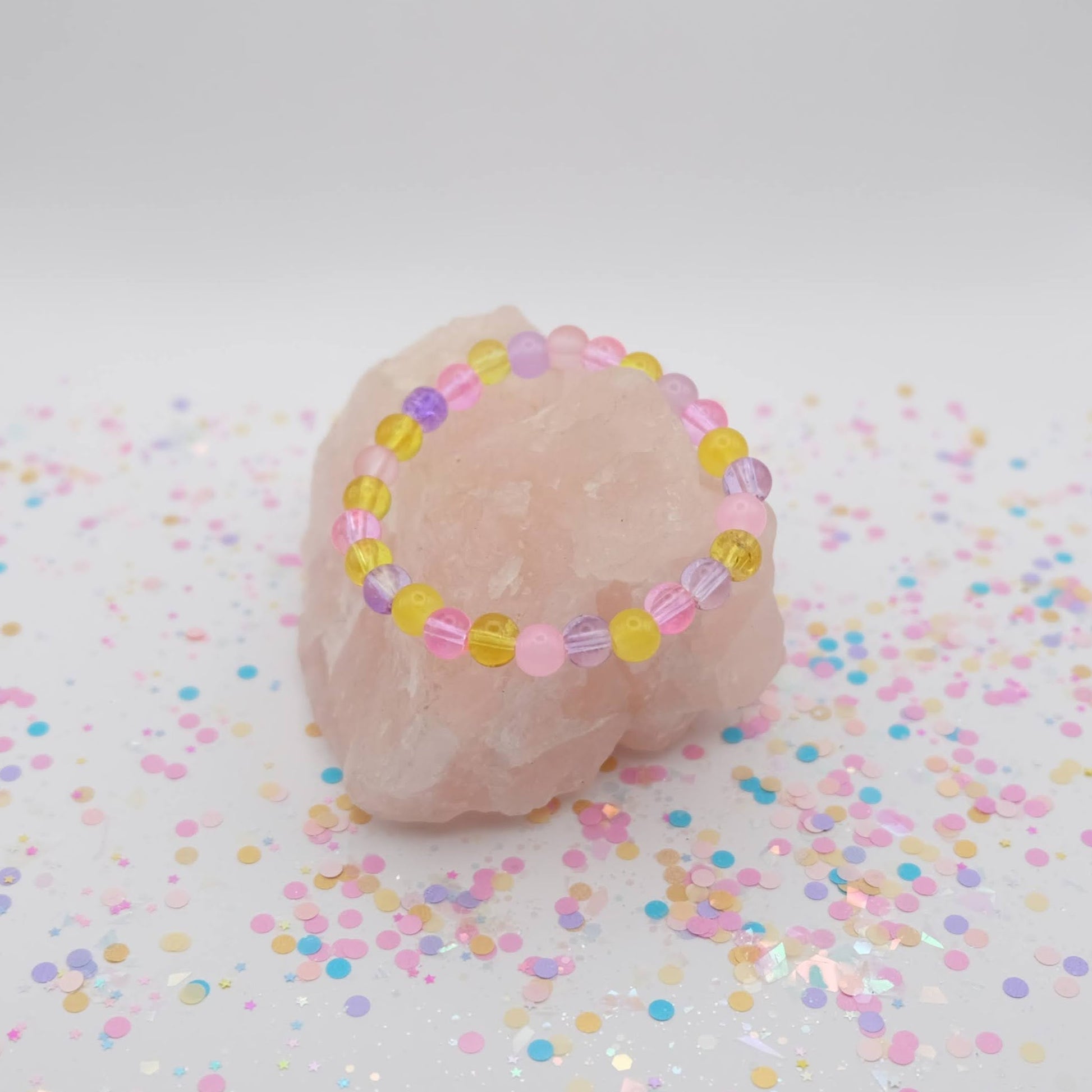Pink, purple and yellow beaded necklace on a white background with confetti