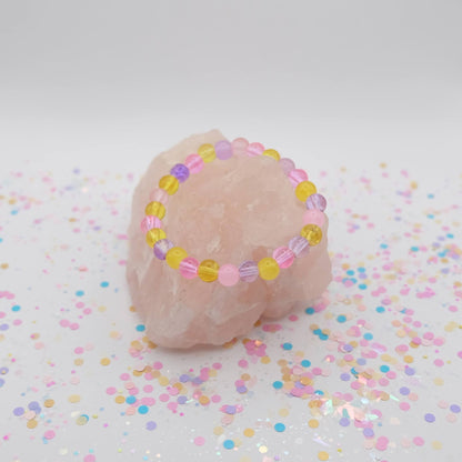 Pink, purple and yellow beaded necklace on a white background with confetti