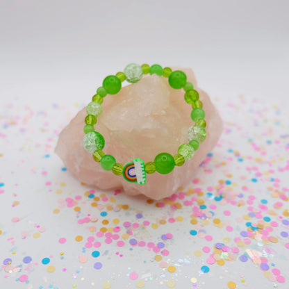 Green beaded bracelet with a polymer clay rainbow bead on a pink stone with colorful confetti