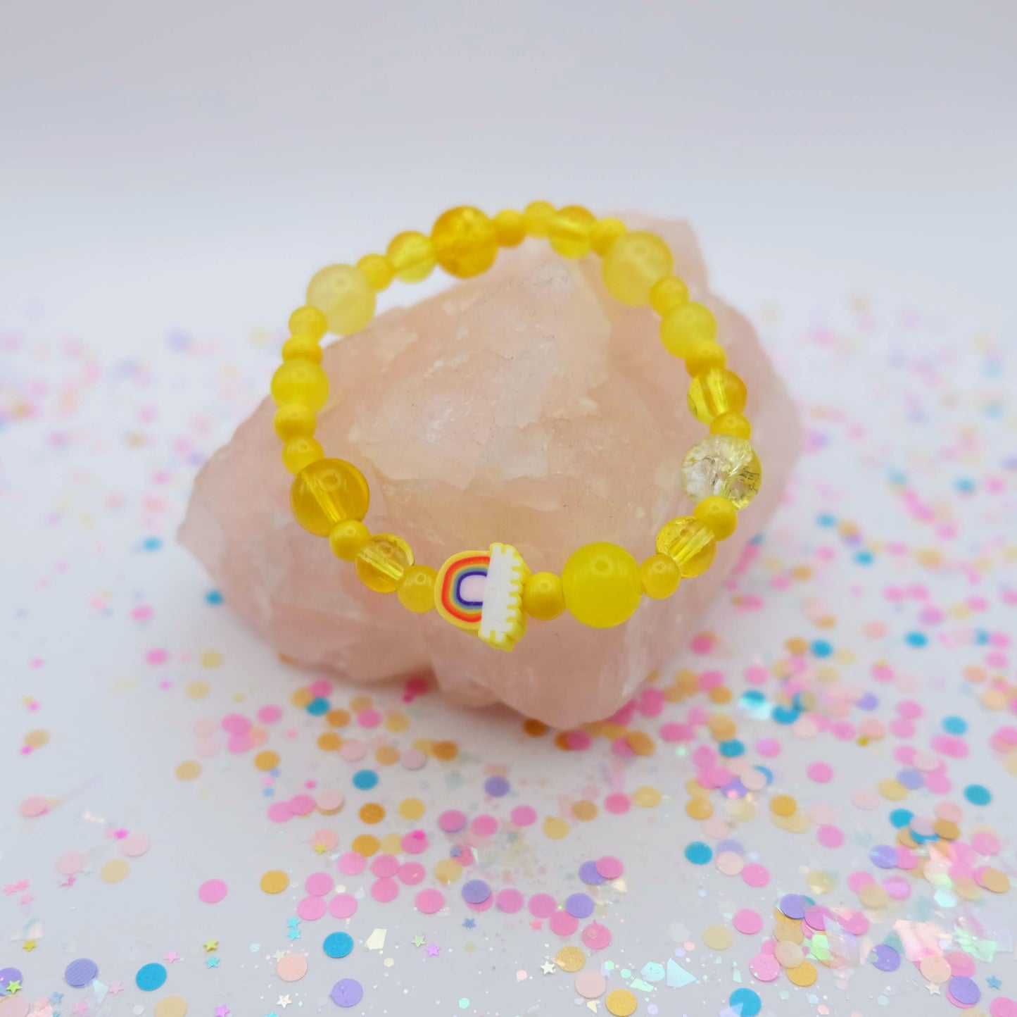 Yellow beaded bracelet with a polymer clay rainbow bead on a pink stone with colorful confetti