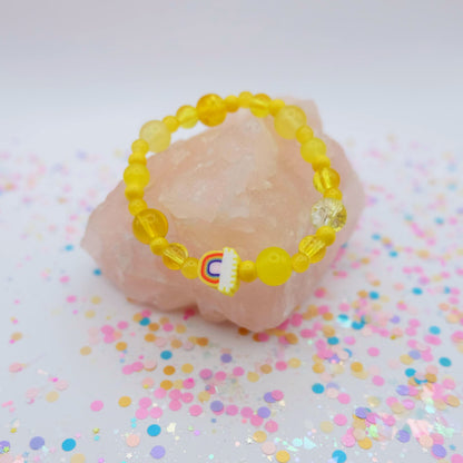 Yellow beaded bracelet with a polymer clay rainbow bead on a pink stone with colorful confetti