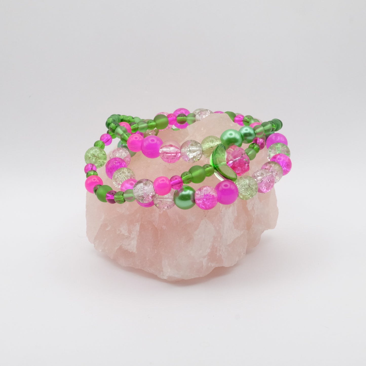 Beaded bracelets with pink and green beads on a rose quartz crystal
