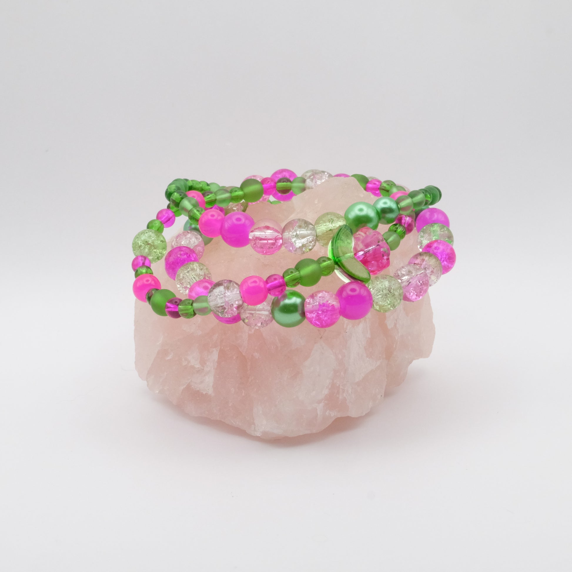 Beaded bracelets with pink and green beads on a rose quartz crystal