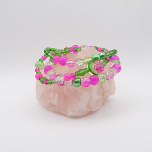 Beaded bracelets with pink and green beads on a rose quartz crystal