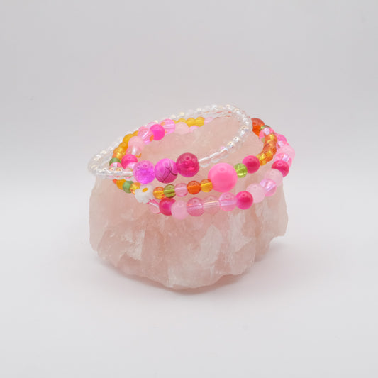 Colorful beaded bracelet on a pink stone with a white background