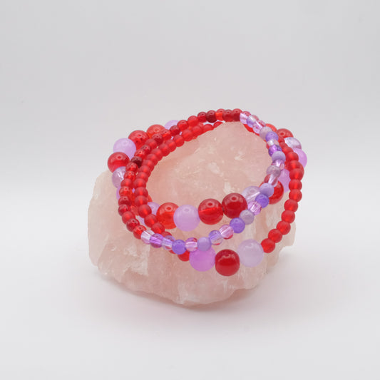 A stack of elastic beaded bracelets in purple and red