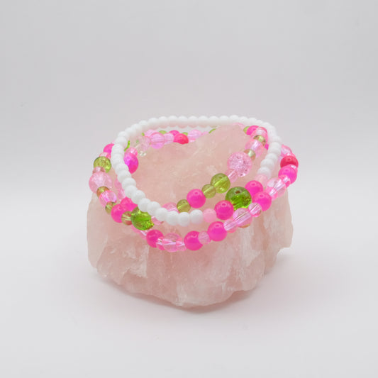 Three beaded bracelets with pink and green beads on a white background