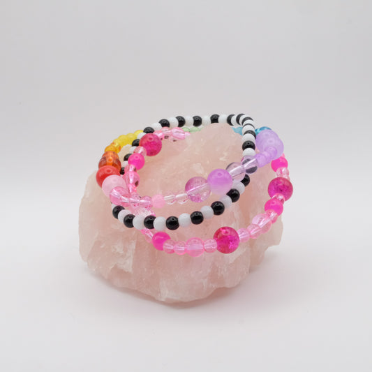 Colorful elastic beaded bracelets on a pink crystal with a white background