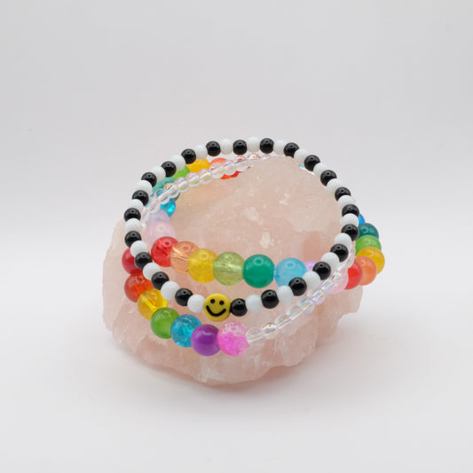Colorful beaded bracelets on a pink stone with a white background