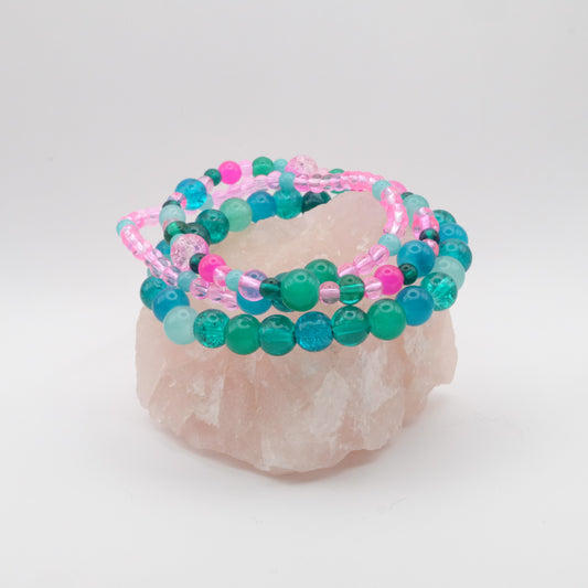 Stack of teal, aqua and pink beaded bracelets on a white background