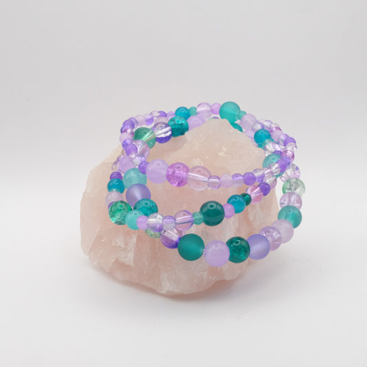 Set of beaded bracelets in purple, teal and aqua on a white background