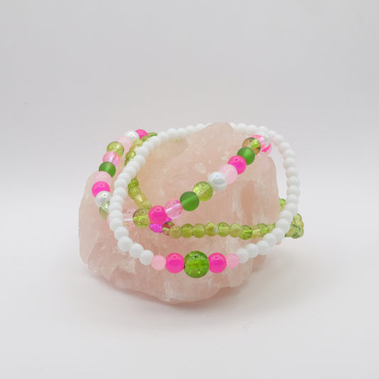 Beaded bracelets with pink and green beads on a white background