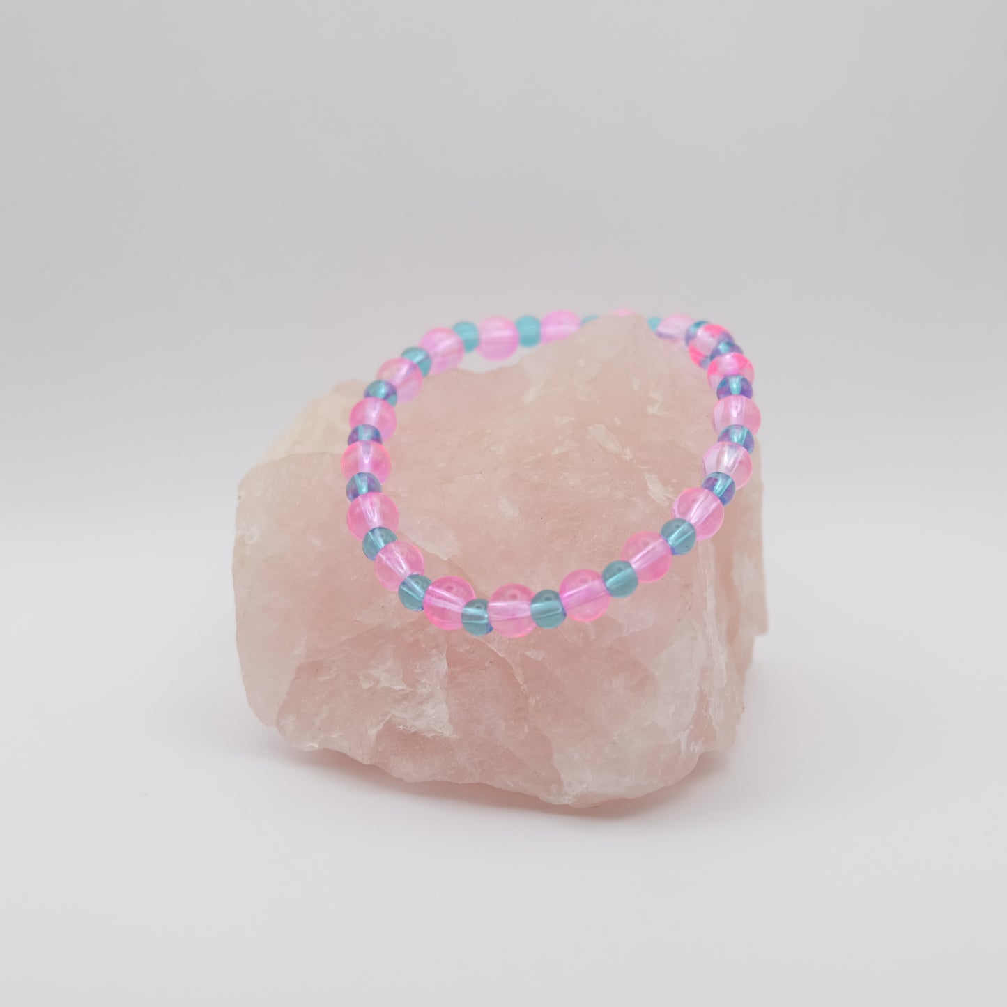 Beaded bracelet with pink and blue beads on a rock against a white background