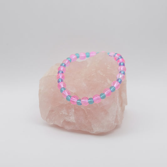 Beaded bracelet with pink and blue beads on a rock against a white background