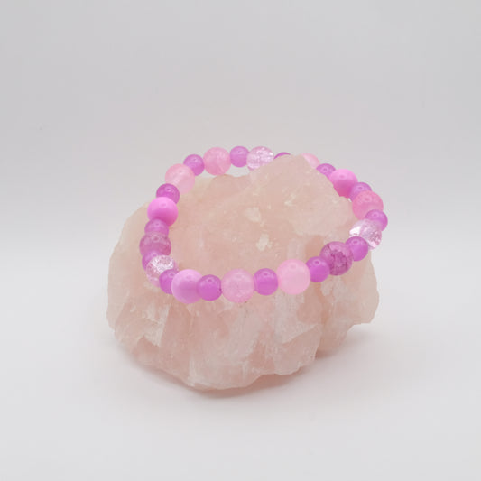 Pink beaded bracelet on a rose quartz stone with a white background