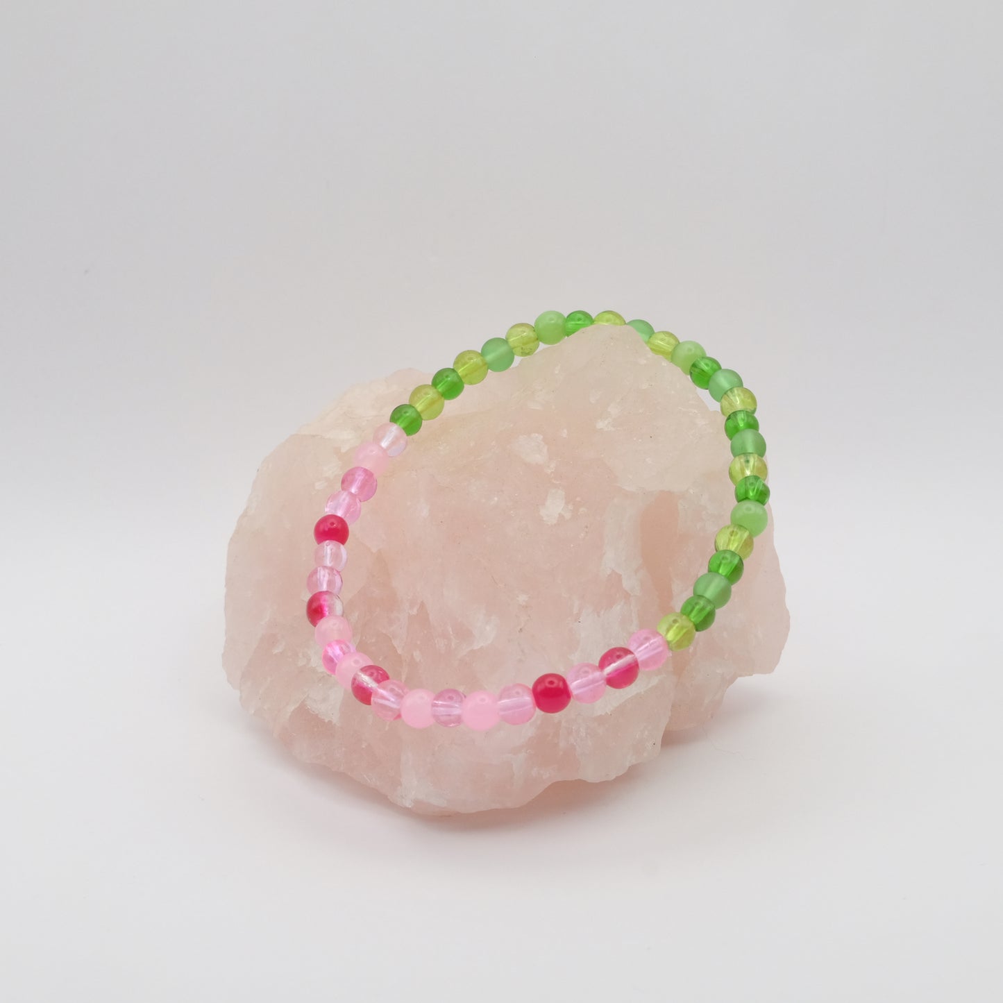 Beaded bracelet with pink and green beads on a stone surface