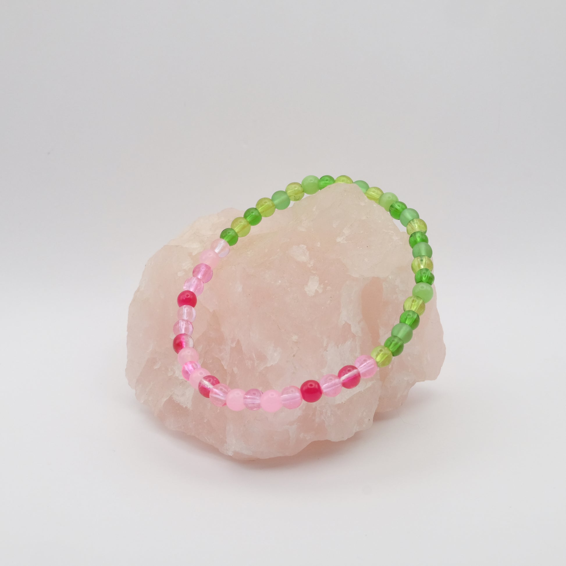 Beaded bracelet with pink and green beads on a stone surface