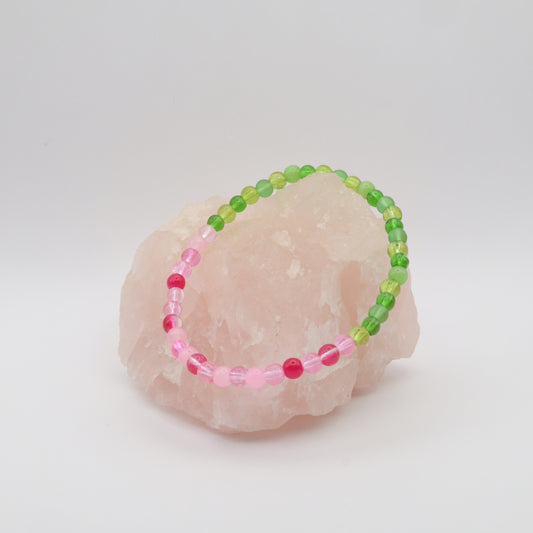 Beaded bracelet with pink and green beads on a stone surface
