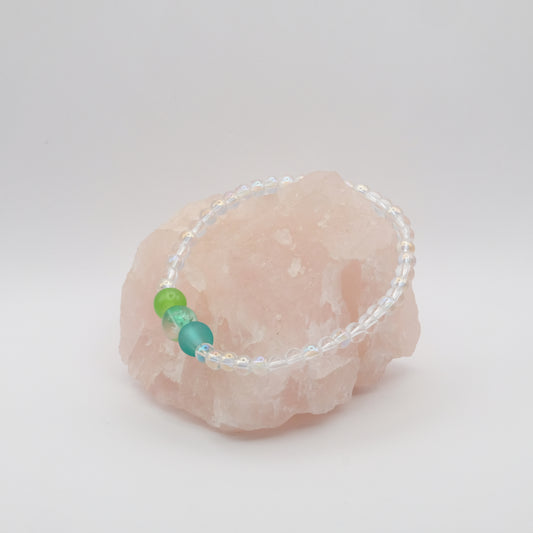 Bracelet with green and blue beads on a pink stone against a white background
