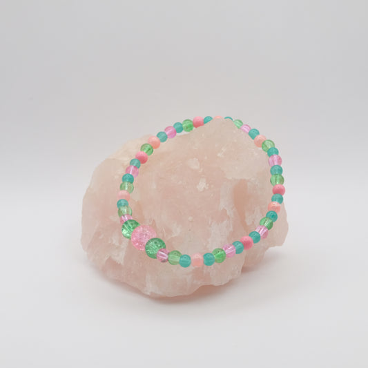 Beaded bracelet with pink and green beads on a pink stone against a white background