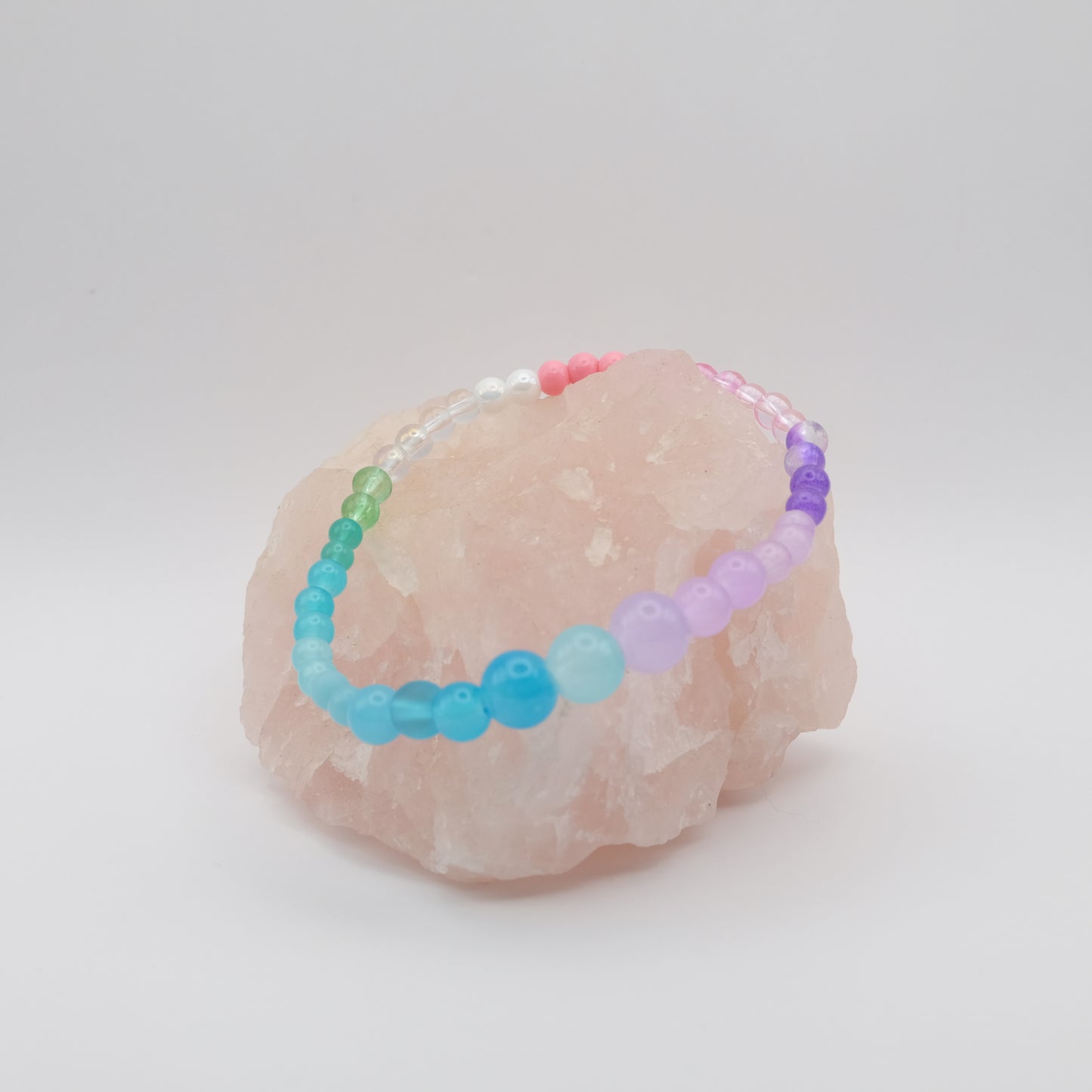 Colorful beaded bracelet on a pink stone with a white background