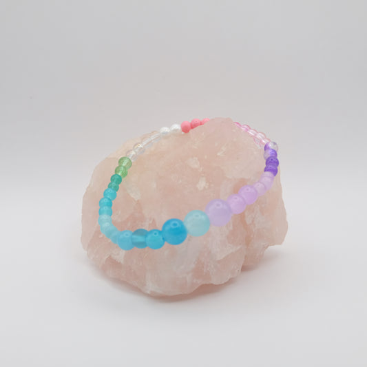 Colorful beaded bracelet on a pink stone with a white background