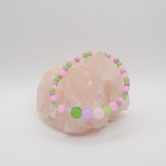 Colorful beaded bracelet on a pink stone with a white background