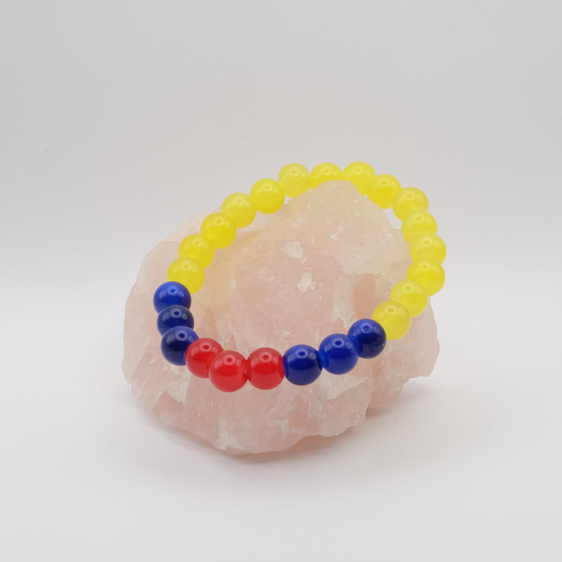 Colorful beaded bracelet on a pink stone with a white background