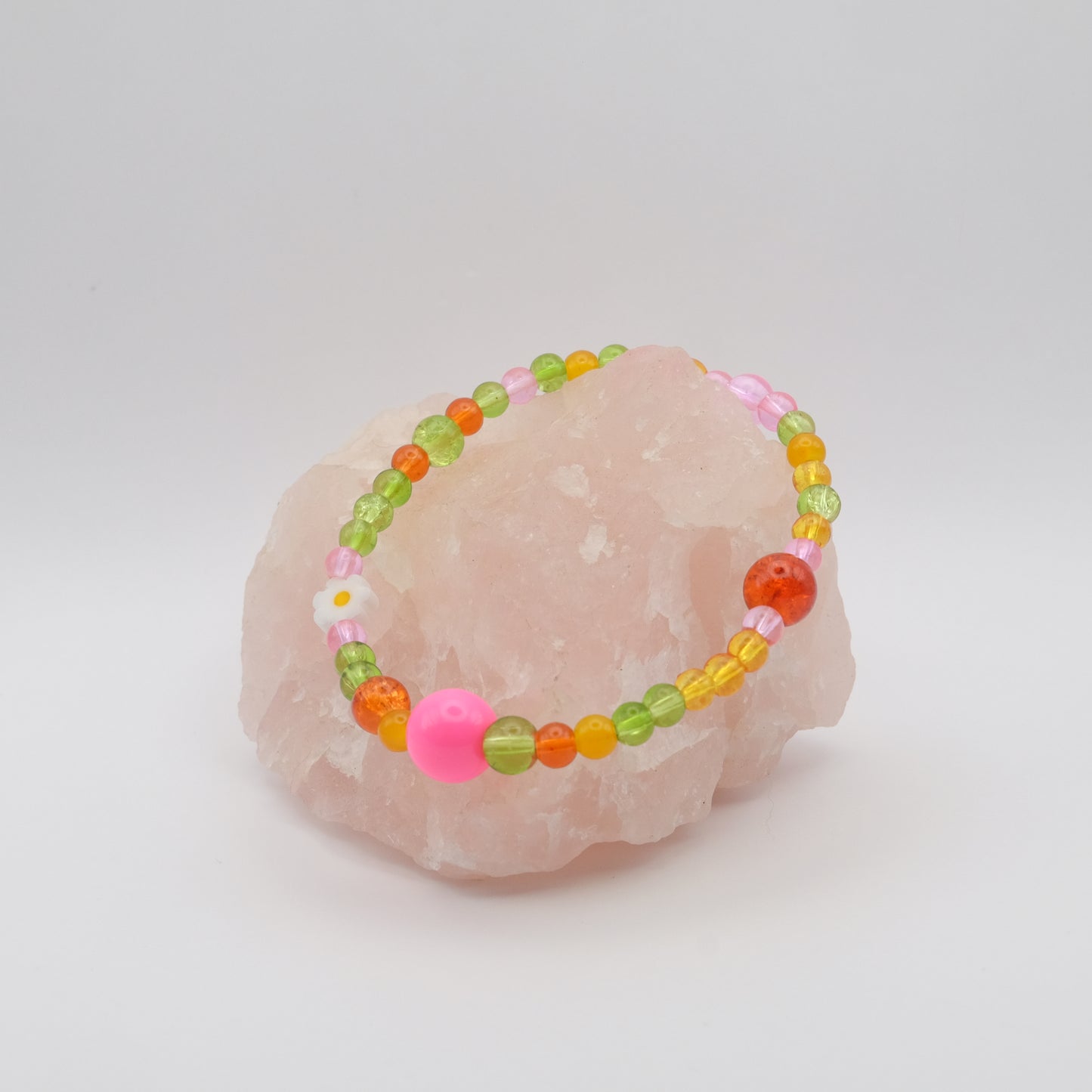 Colorful beaded bracelet on a pink stone with a white background