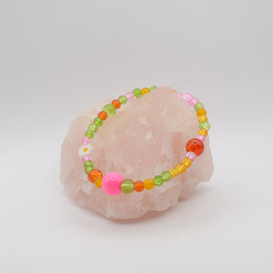 Colorful beaded bracelet on a pink stone with a white background