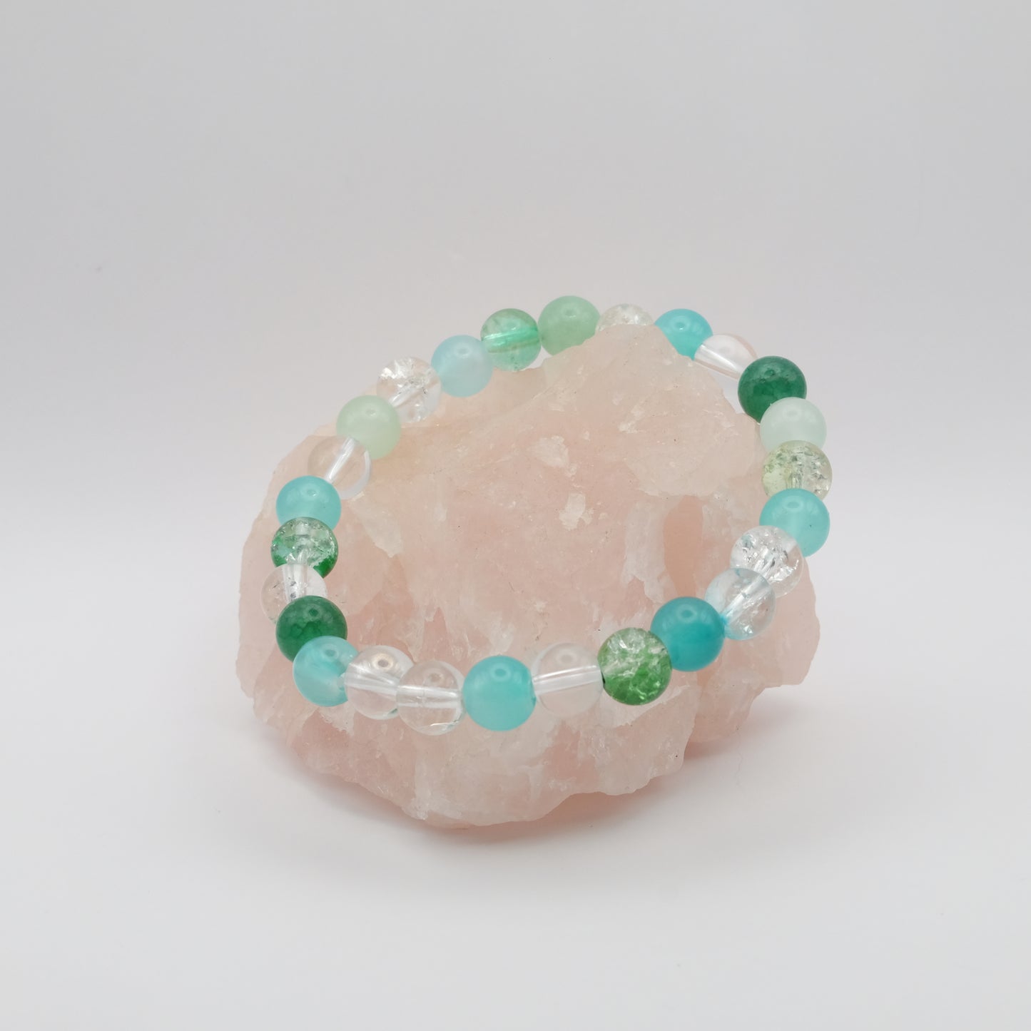 Beaded bracelet with green and blue beads on a pink crystal