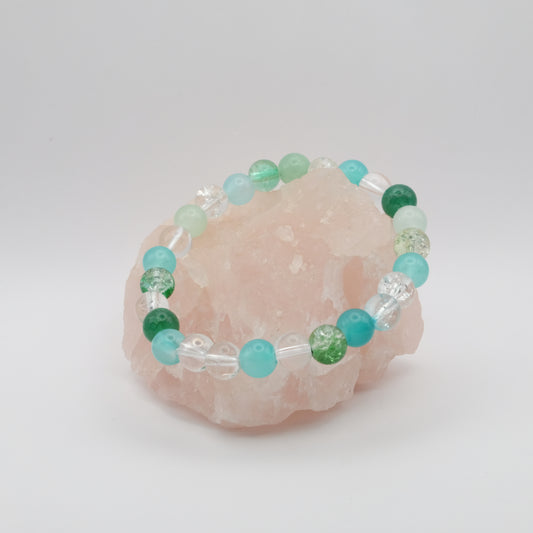 Beaded bracelet with green and blue beads on a pink crystal