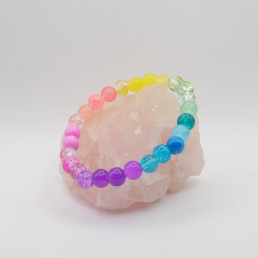 Colorful beaded bracelet on a pink crystal with a white background