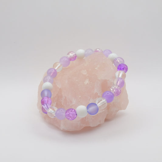 Beaded bracelet with purple and white beads on a pink stone